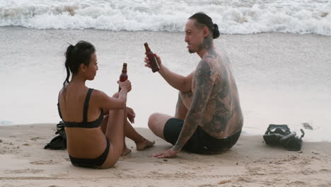 una pareja bebiendo cerveza en la playa.