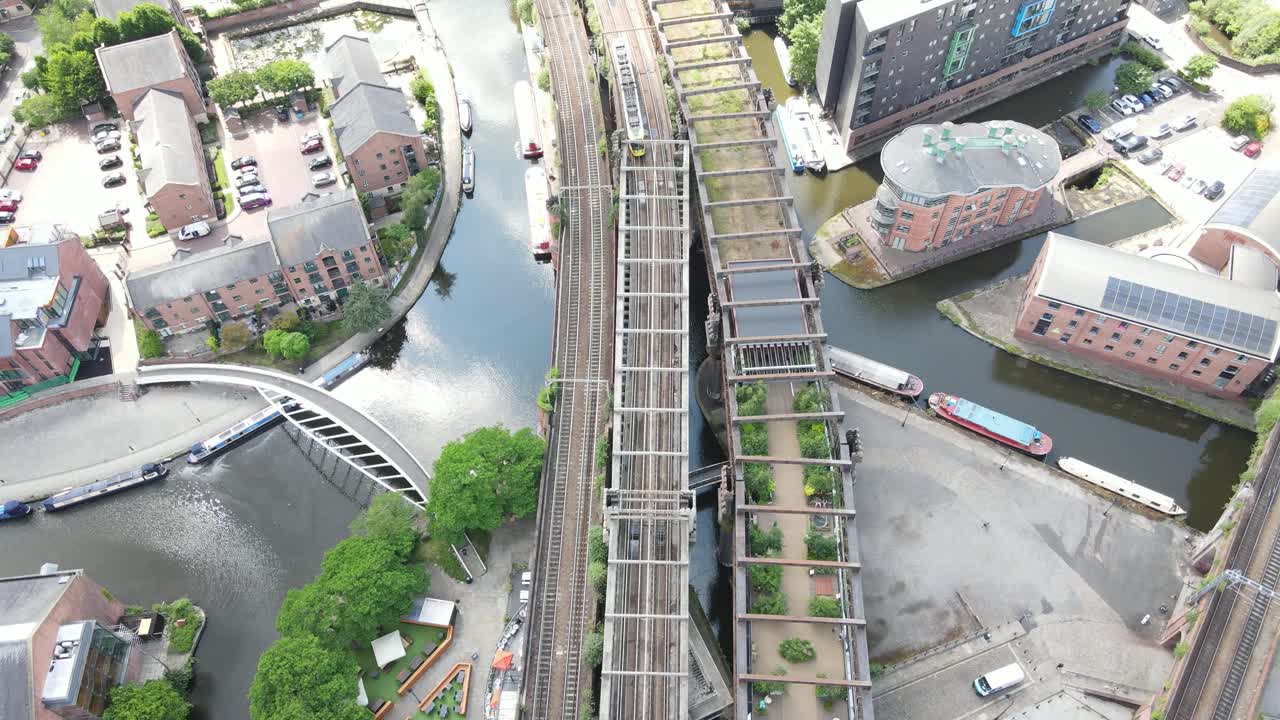Aerial drone flight over the rooftops of Castlefield Quays in Manchester City Centre with a view of a moving tram below