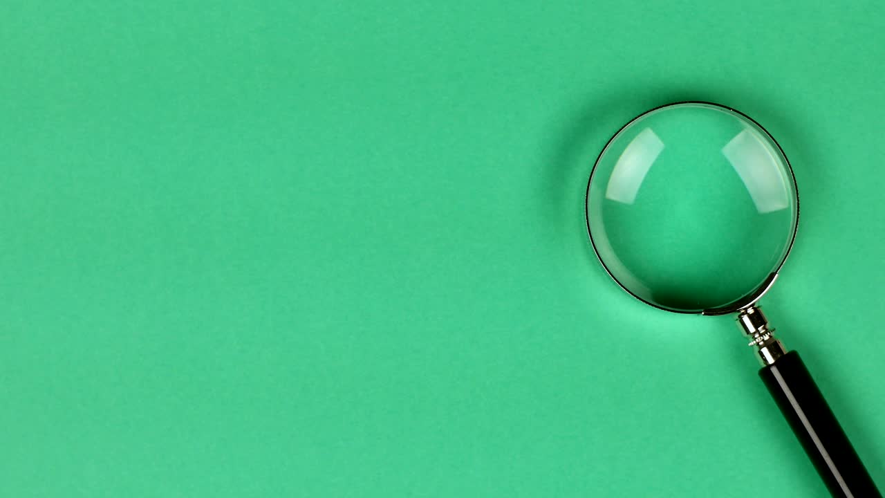 colocación a mano de una lupa sobre un fondo verde para mostrar la búsqueda o la investigación