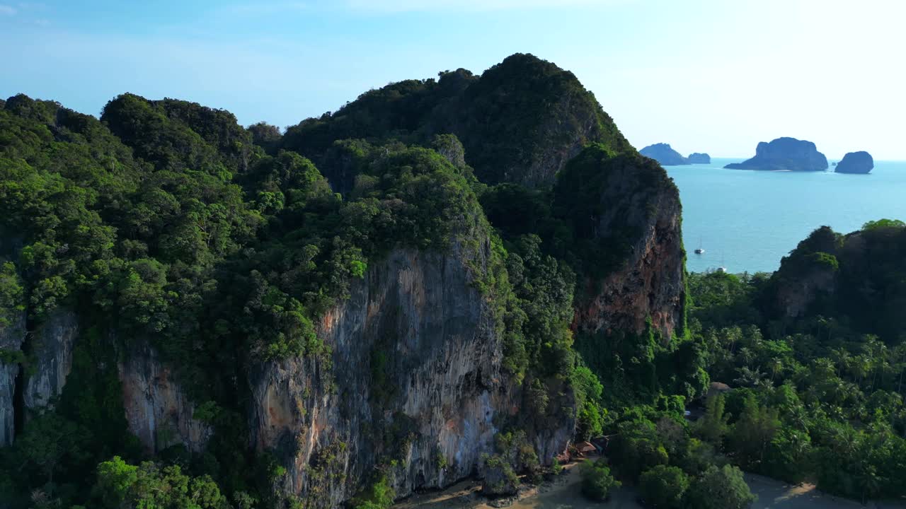 Floating pier connecting Railay West and Railay East during low tide, surrounded by limestone mountains and tropical vegetation. Fabulous aerial view flight fly reverse drone