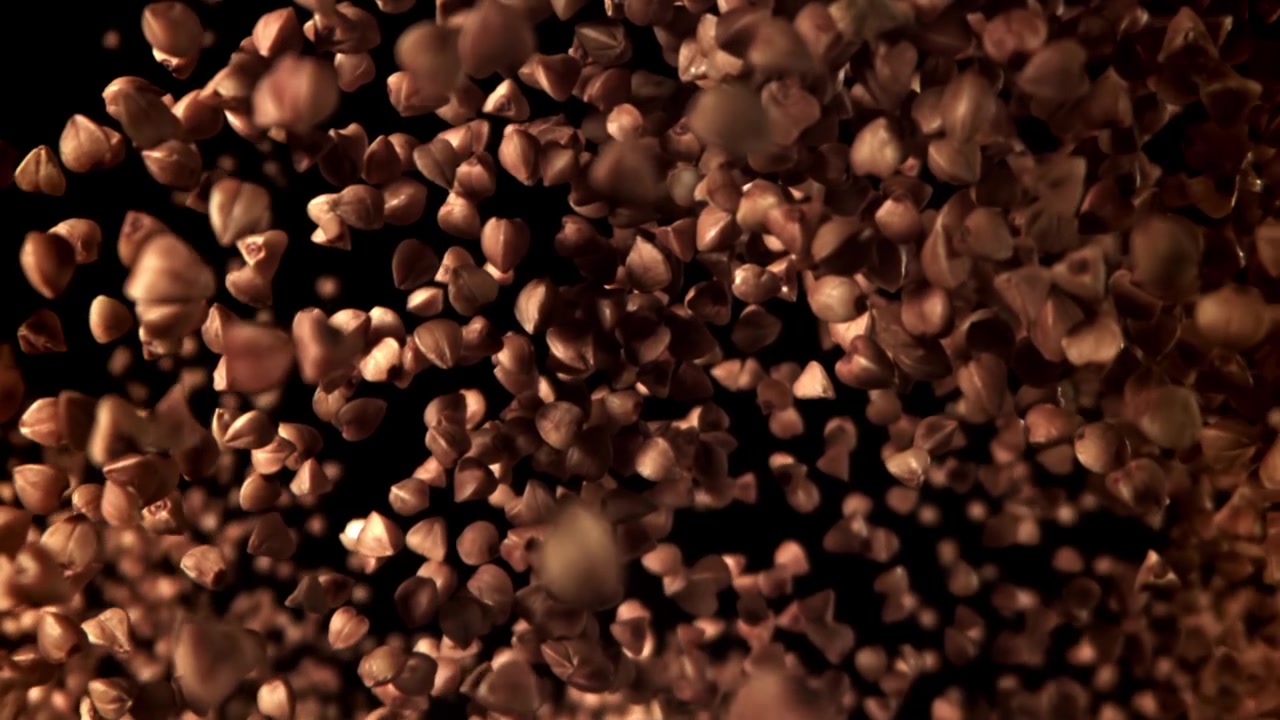 Grani di grano saraceno in caduta al rallentatore su sfondo nero