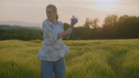 happy woman with flowers dancing at golden sunset