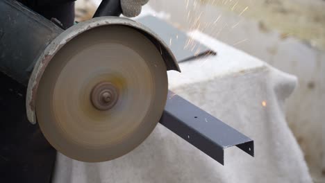 man works circular saw. sparks fly from hot metal. craftsman sawing steel with disk grinder outdoors.