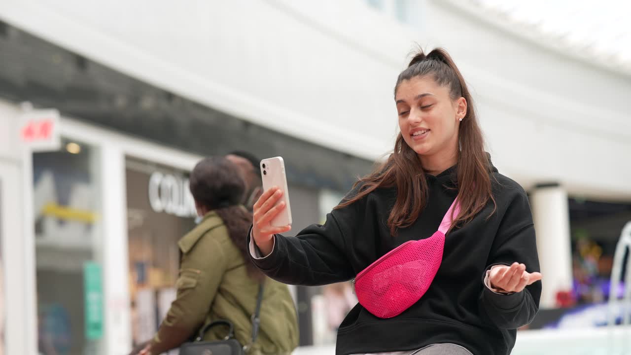 adolescente haciendo video llamadas en el centro comercial