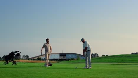 golf team play sport on green grass field club. two golfers teeing hitting ball.