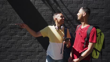 dos felices amigos de raza mixta usando un teléfono inteligente en la calle