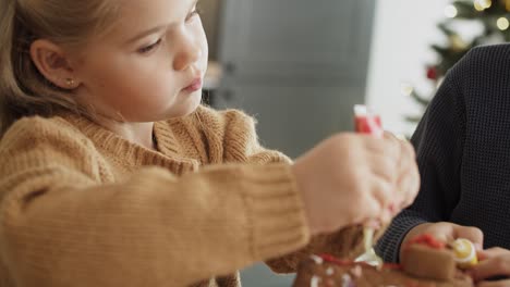 video of little girl focused on decorating gingerbread house