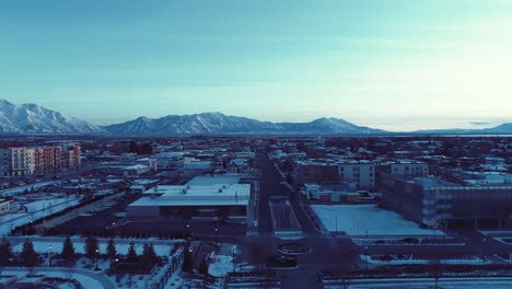 sweep through building tops in provo utah during dusk blue hour with the sunlight barely peaking over the hills - aerial dolly through buildings