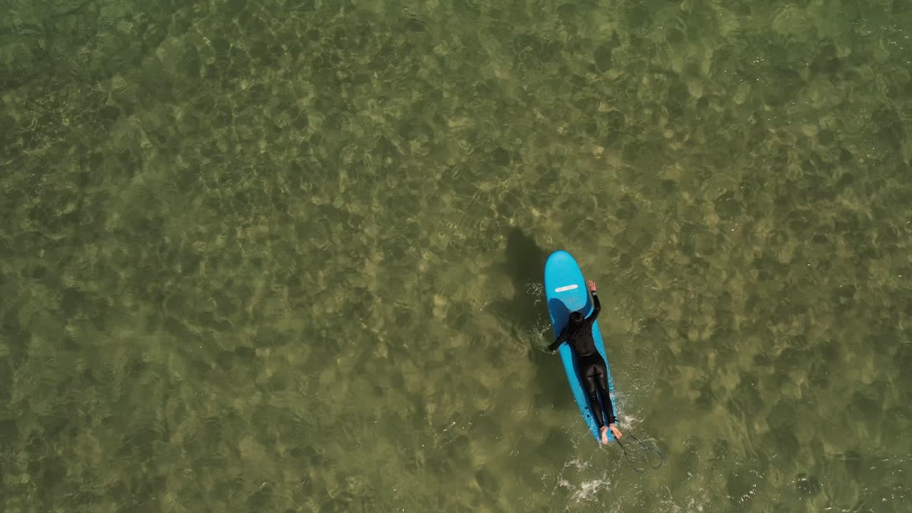 Topdown view female paddling on blue Longboard on Clear water, Slow motion shot