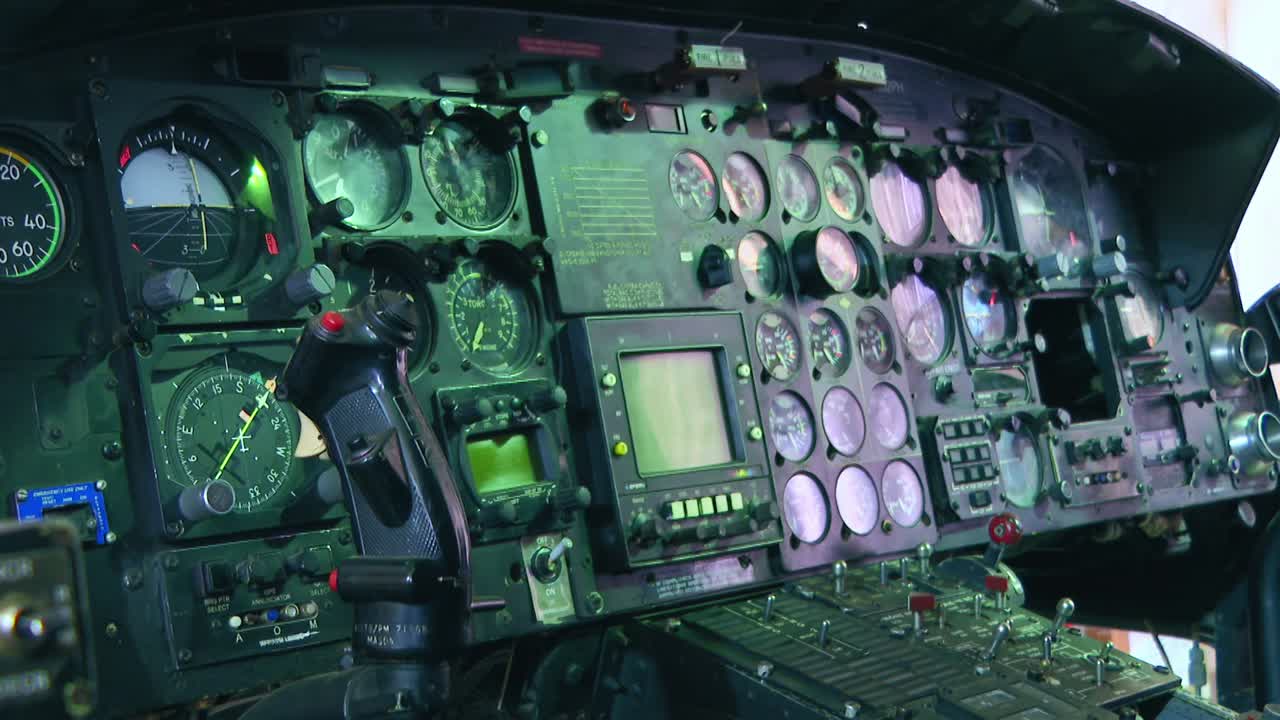 Detailed view inside a vintage military helicopter cockpit. The shot pans over the complex instrument panel, showing various gauges, dials, and switches