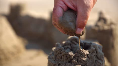 primer plano de la mano haciendo castillos de arena en la playa