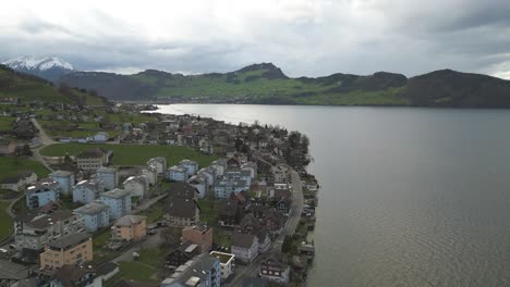 Aerial-View-of-Beckenried-Municipality-at-Shore-of-Lake-Lucerne,-Switzerland-on-Cloudy-Spring-Day,-Drone-Shot