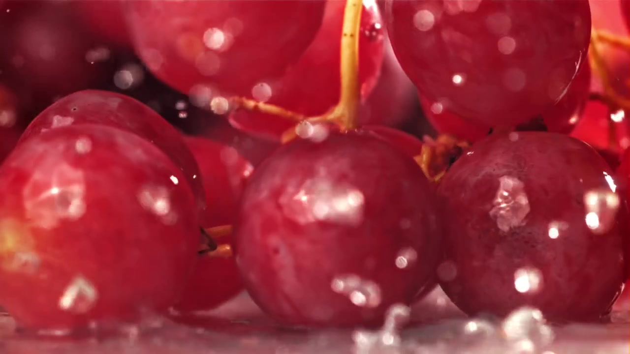 Uva rossa fresca che schizza nell'acqua al rallentatore