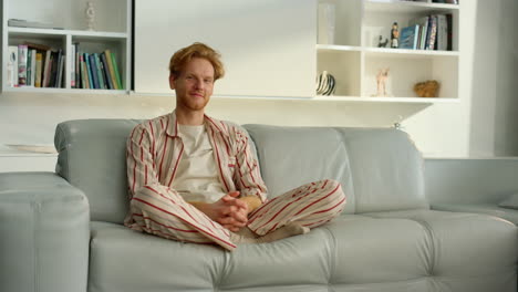 bachelor man enjoy weekend at home. joyful ginger freelancer resting in pajamas