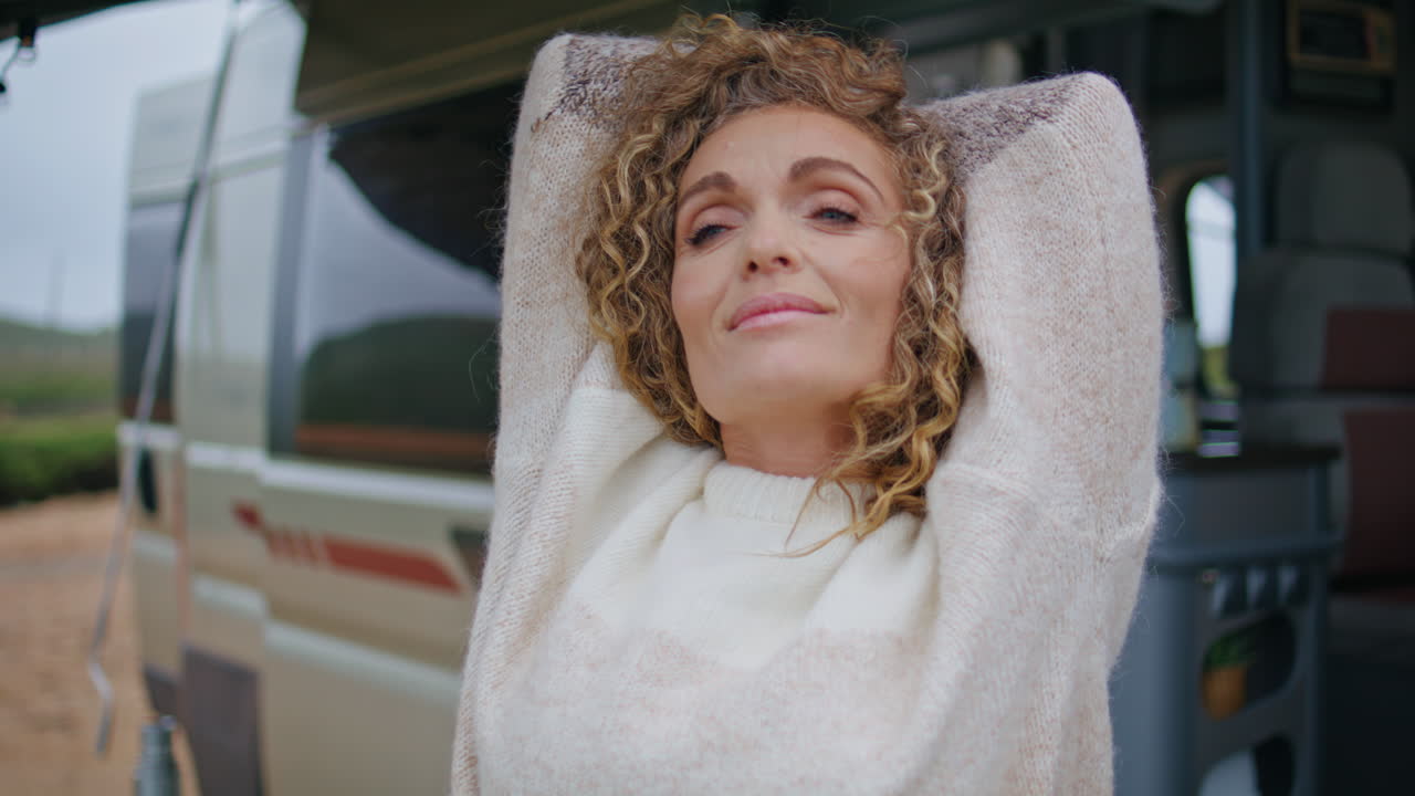 평온 한 여자 가 캠퍼 밴 을 포즈 하고 행복 한 미소 로 카메라 를 바라보고 있다