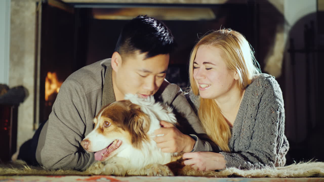 젊은 부부는 개 옆에 있는 벽난로 옆에서 쉬고 있다 01