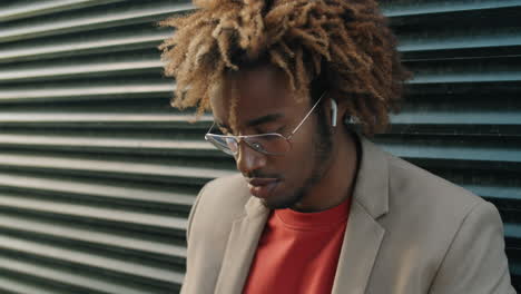 Cheerful-African-American-Man-Using-Laptop-and-Drinking-Coffee-on-Street