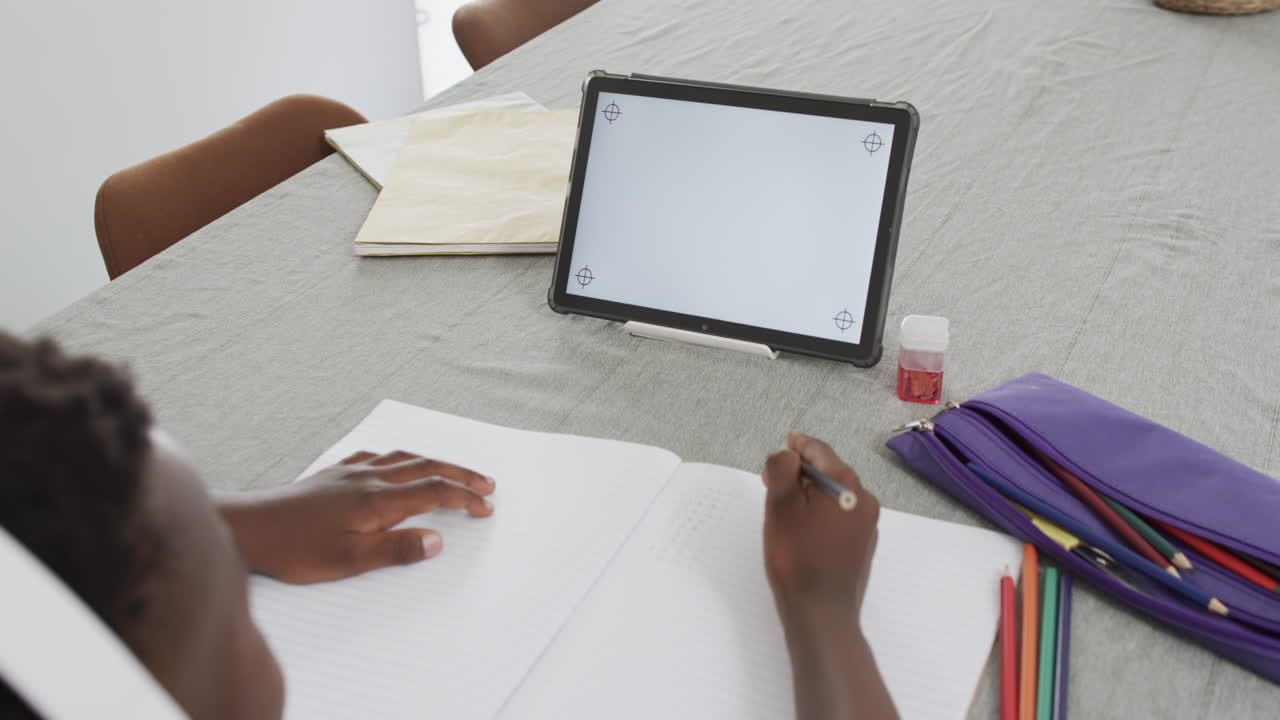 African American boy studies at home using a tablet, with copy space