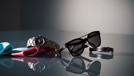 luxury accessories: watch, sunglasses, and fabric on reflective surface