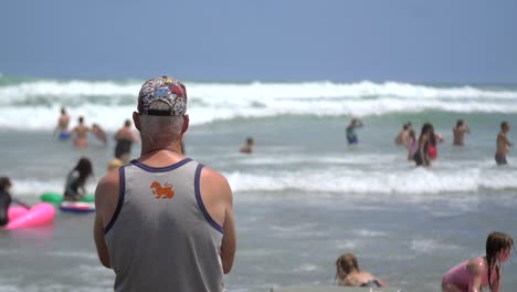 old man overlooking busy beach