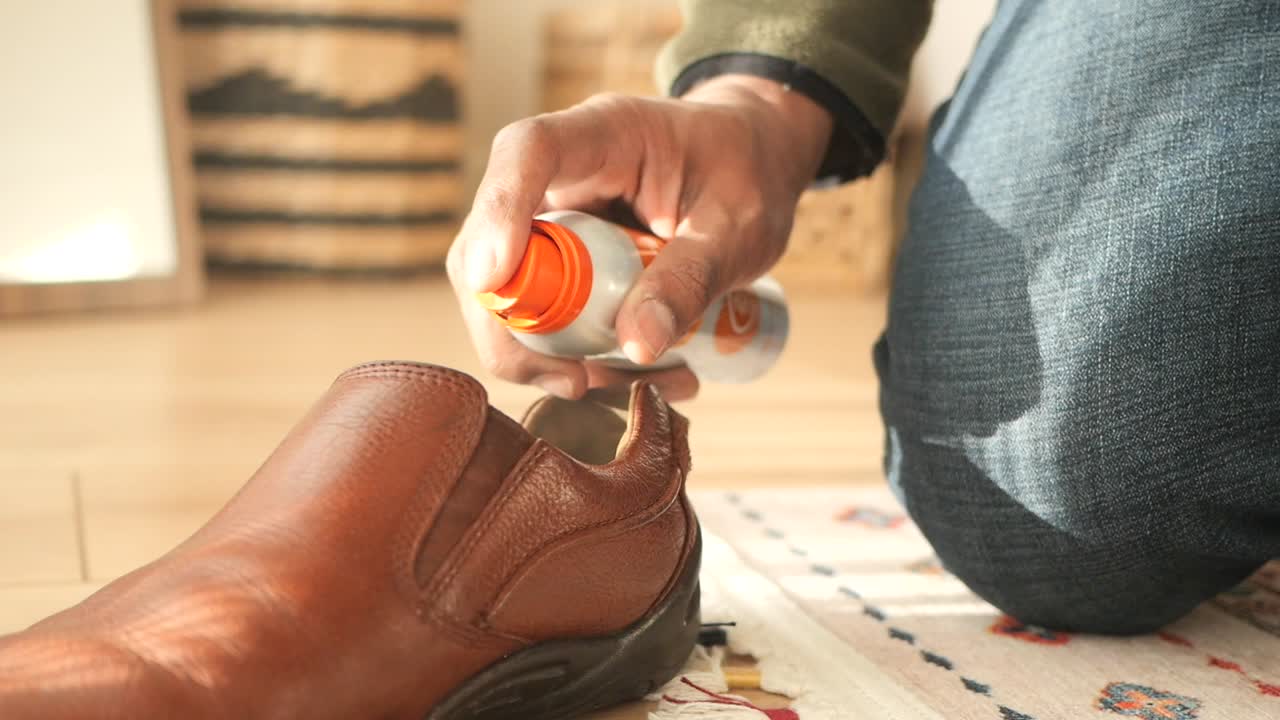 Person som rengjør skinnsko med skospray