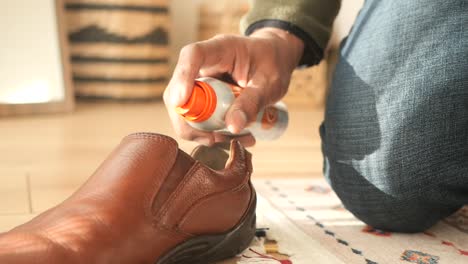 person cleaning leather shoes with shoe spray