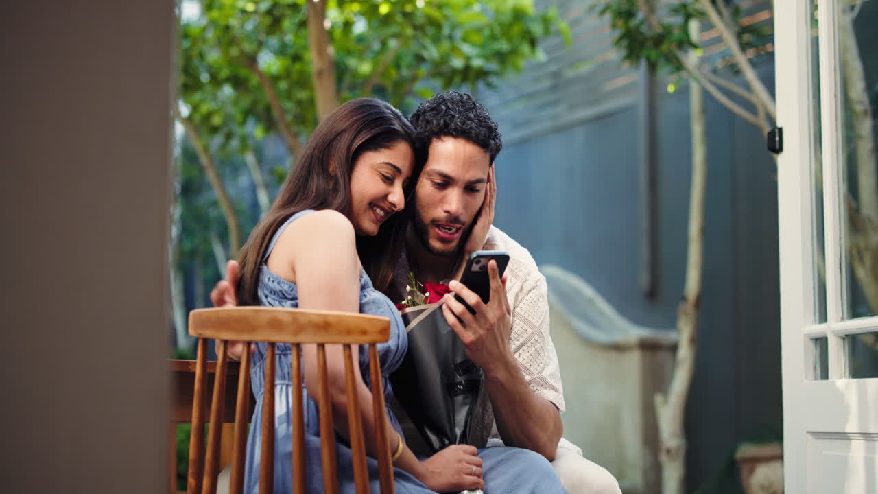 Giovane coppia felice che guarda lo smartphone insieme con fiori