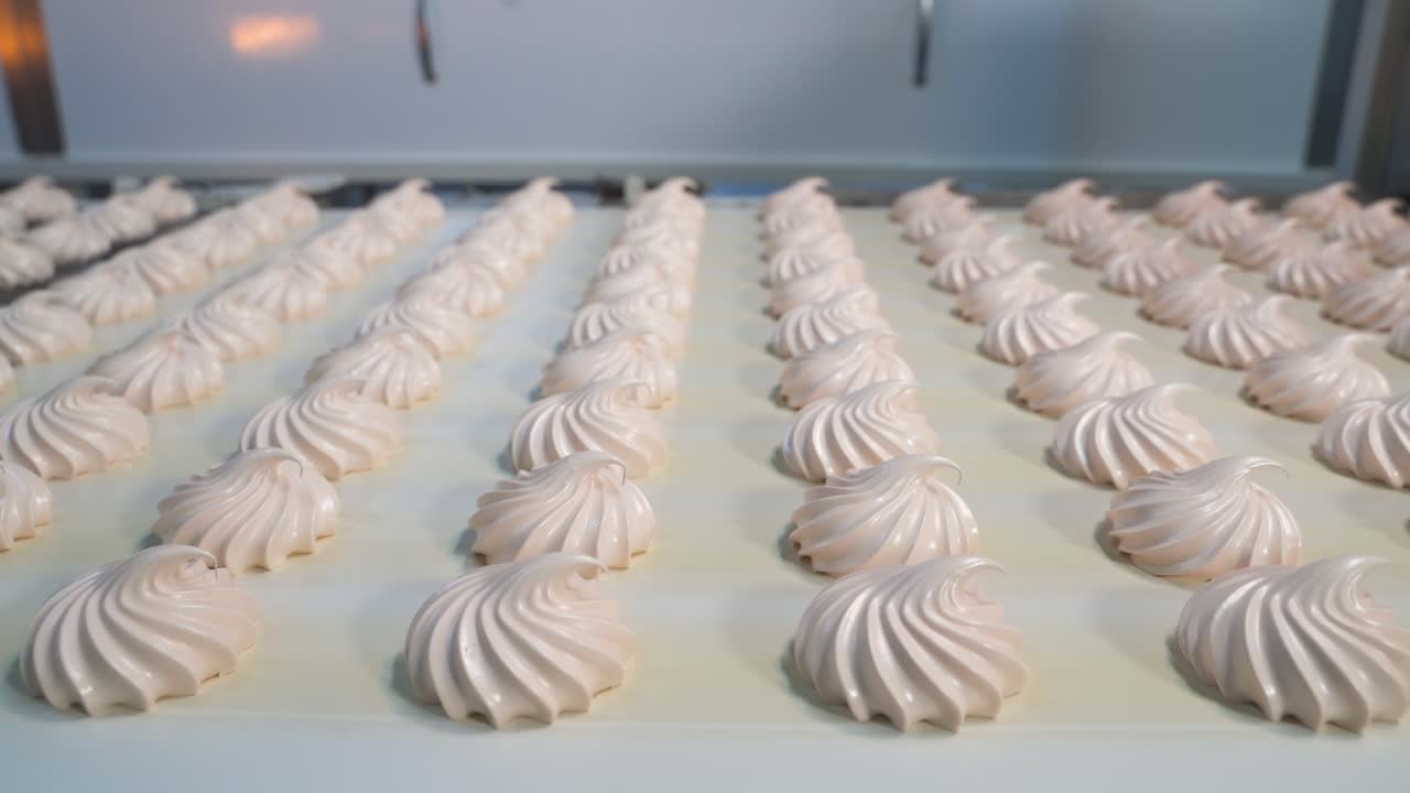 Conveyor belt with sweet white marshmallow souffle at a candy factory. Rows of finished products for sorting