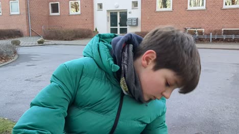 close-up view of young kid removing mud from his hiking boots after being in the forest