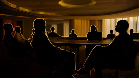 silhouettes of business people in a golden-lit meeting room