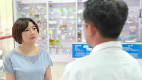 male doctor pharmacist smiling presenting and recommending medical pills in blister in a pharmacy store drug