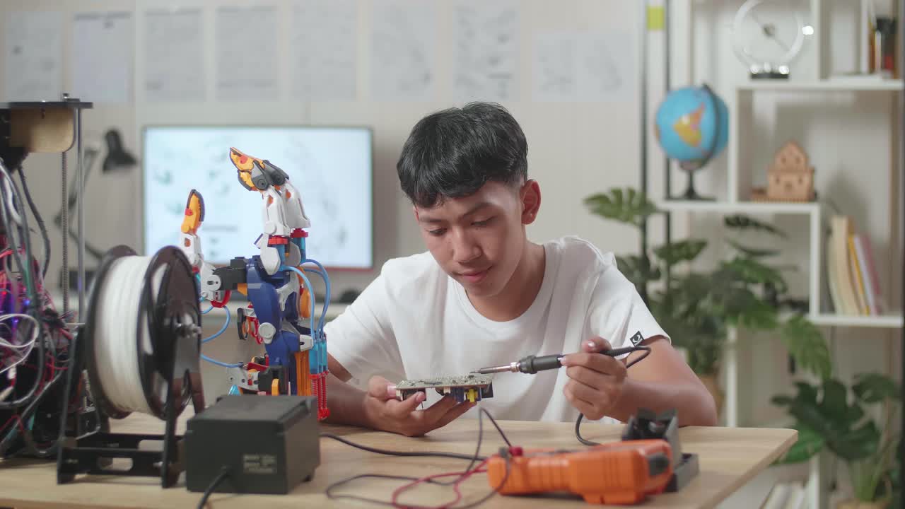 niño asiático sosteniendo y arreglando la placa de circuito mientras repara una mano de cyborg en casa
