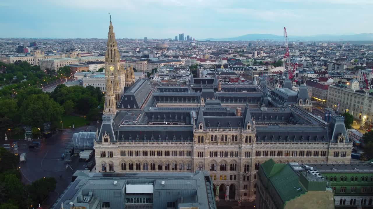 드론이 시계탑을 확대하고 도시를 배경으로, 부드러운 저녁 빛과 하늘을