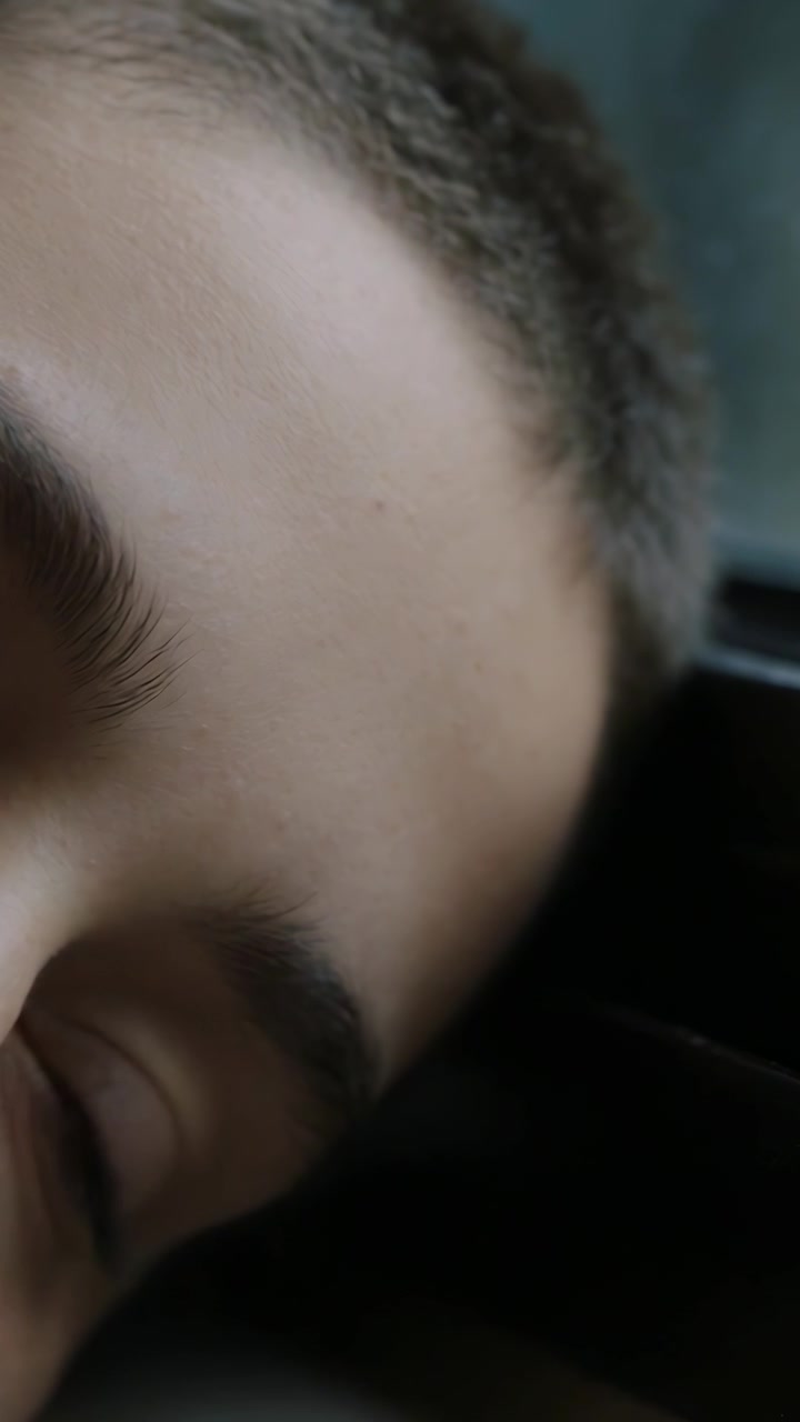 Video verticale: Volto di adolescente che ammicca con l'occhio sinistro all'interno di un'auto, con una telecamera nelle vicinanze.