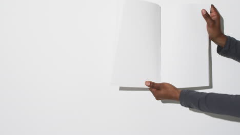 video of hand of african american man holding book with blank pages, copy space on white background