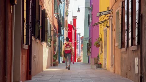 walking through burano: young tourist marvels at colorful streets and history in venice's picturesque island