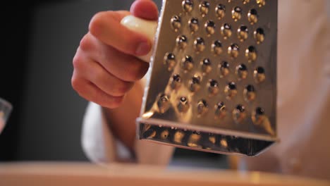 cook rubs the egg on a grater