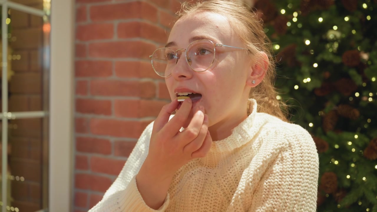 Giovane donna felice che mangia caramelle durante le festività natalizie
