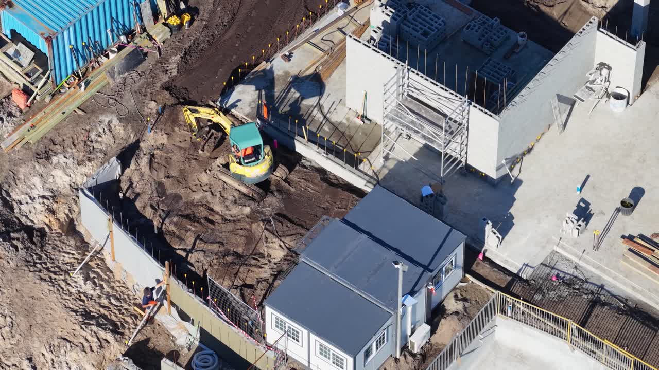 Drone footage captures construction workers and machinery at a building site in Gold Coast, Australia, under clear daylight