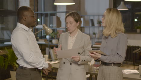 group of three  employees standing in the office and discussing together about business strategy 1