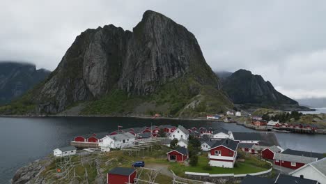 Volando-A-Través-Del-Clásico-Pueblo-Tradicional-De-Pescadores-De-Hamnoy-En-Lofoten,-Noruega-Con-Las-Clásicas-Cabañas-Rojas-De-Rorbuer-Con-Vistas-A-La-Icónica-Montaña-Y-Al-Océano