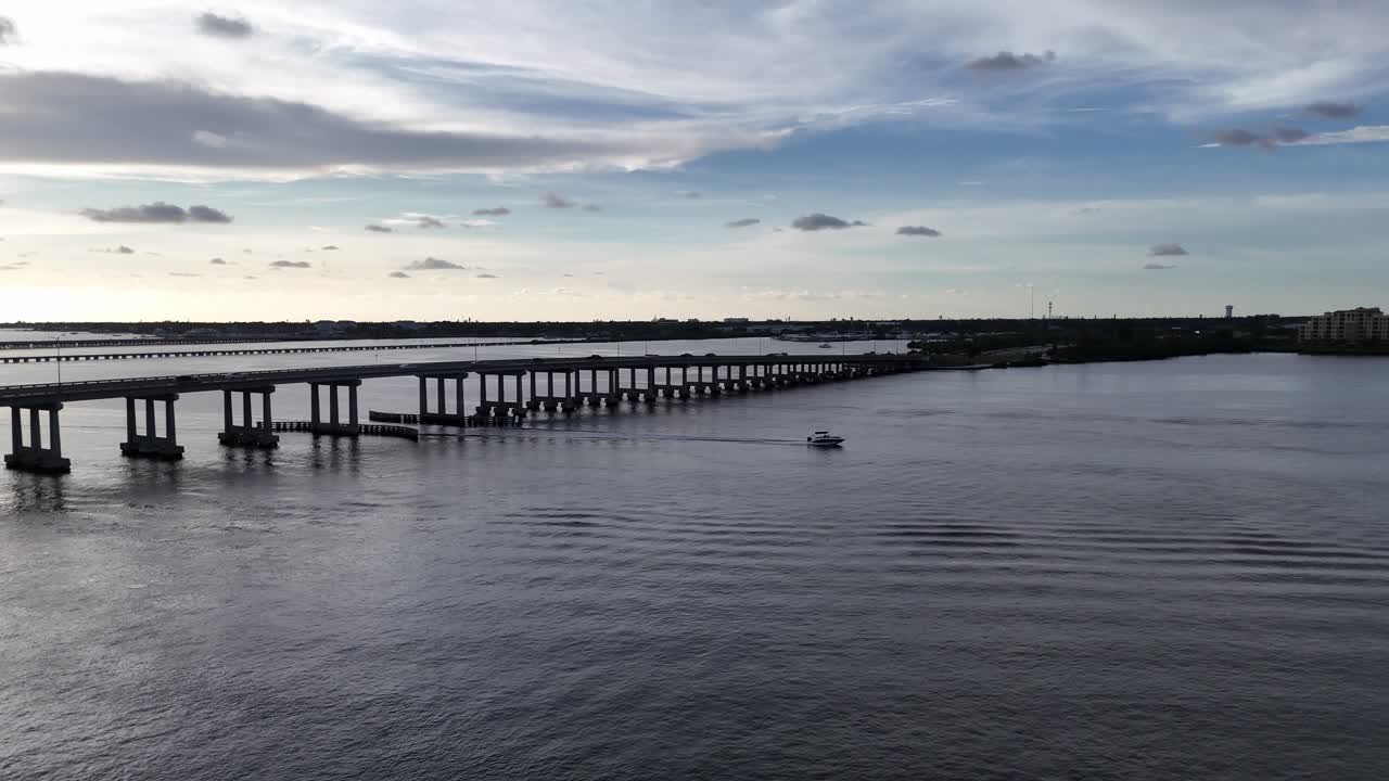 speeding small motorboat speeds under the Manatee River Bridge in Bradenton, Florida racing to get home by sunset