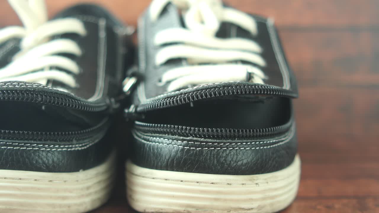 primer plano de zapatillas negras dañadas con cremalleras abiertas