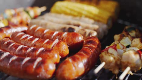 salchichas, mazorcas de maíz y kebabs a la parrilla en una barbacoa