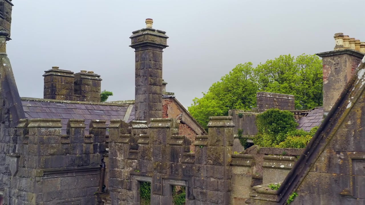 Panoramica aerea sulla linea del tetto del Castello Saunderson che mostra parapetti merlati, comignoli decorativi e dettagli di fortificazioni in pietra.