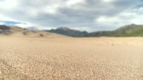 close up sand grains in desert with mountain range background