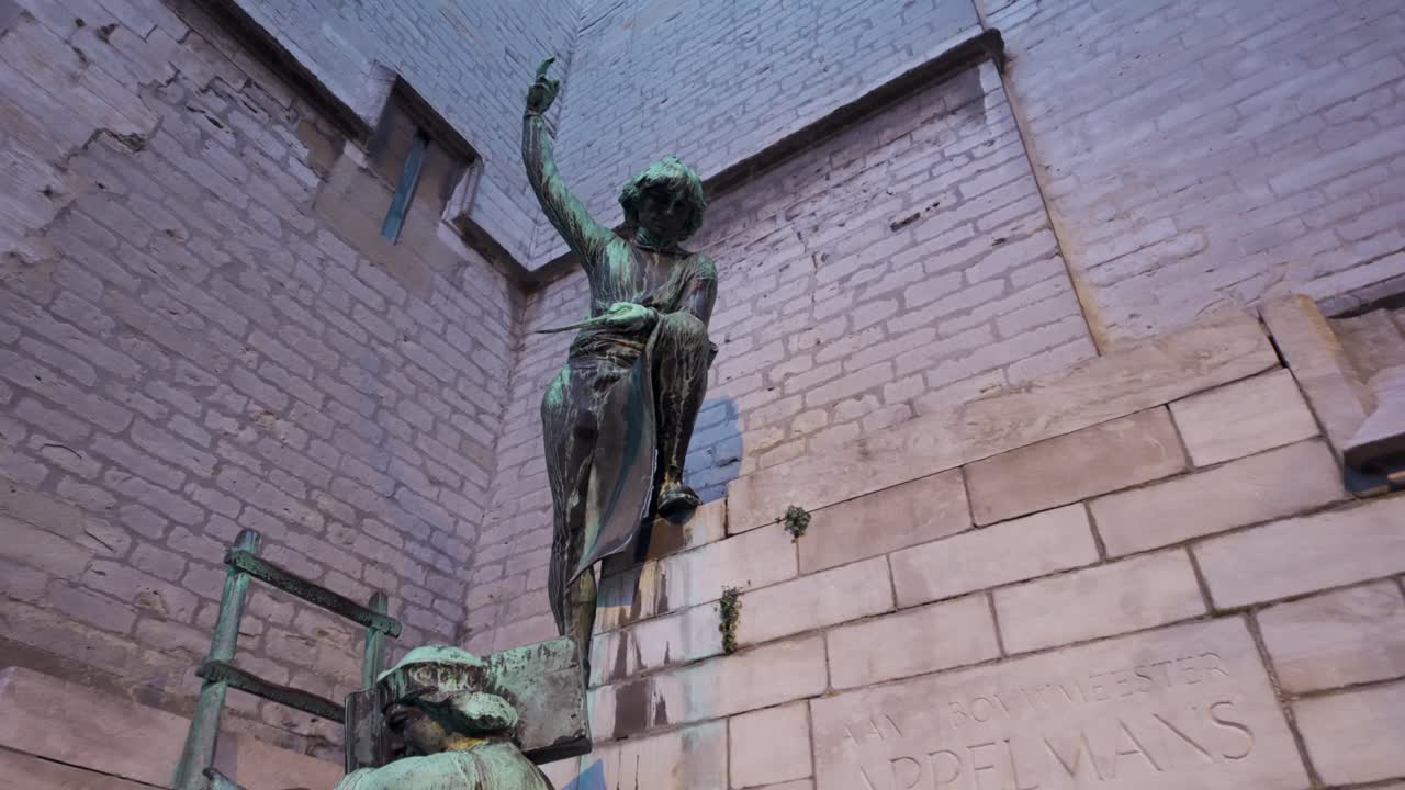 Pieter Appelmans monument in Antwerp. Bronze statues of medieval stonemasons and architects with stone wall in background near the Cathedral of Our Lady