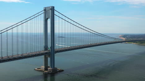 aerial view of the verrazano bridge as the drone camera pans right viewing staten island and the waters below on a sunny morning, orbit 2