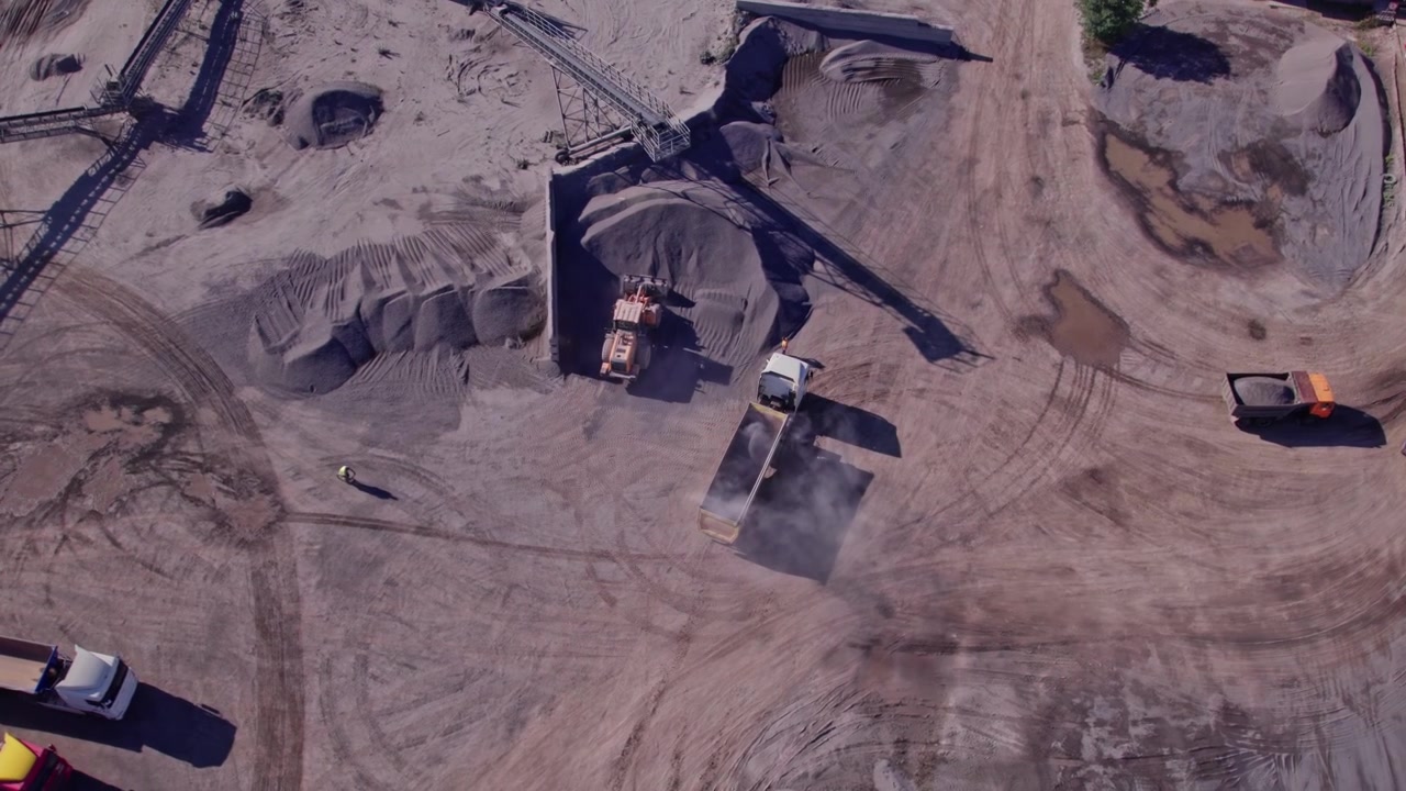 Workers move materials at a quarry site during the day