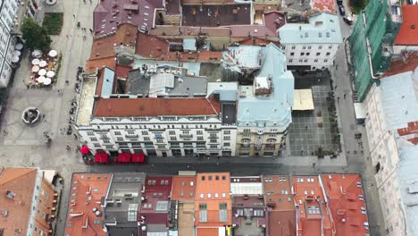 Vista-De-Arriba-Hacia-Abajo-De-La-Plaza-Rynok-En-Lviv-Ucrania-Rodeada-De-Edificios-Europeos-Y-Gente-Caminando-Por-Las-Calles-Durante-Un-Día-De-Verano